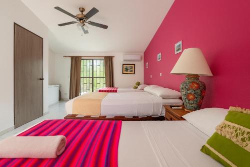 een slaapkamer met 2 bedden en een roze muur bij Villa México a 5 Minutos de la playa in Cancun