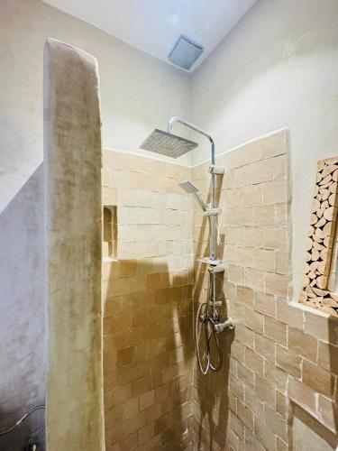 a shower in a bathroom with a brick wall at Natural Surf Morocco in Tamraght Ouzdar