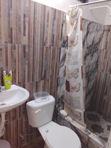 a bathroom with a toilet and a sink and a shower curtain at Villa comoda in Puerto López
