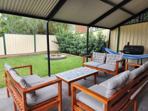 a patio with four chairs and a table and a grill at Cozy Getaway with private backyard in Penrith