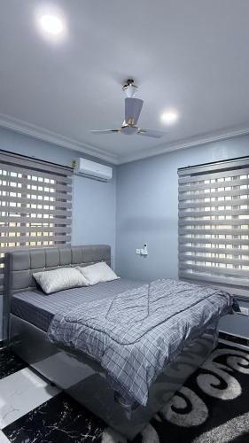 a bedroom with a bed with blue walls and a ceiling at Cozy 2-bedrooms in Lakeside Estate Accra in Apenkwa