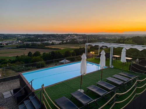 a view of a pool with chairs and umbrellas at Villa Bordone in Tigliole