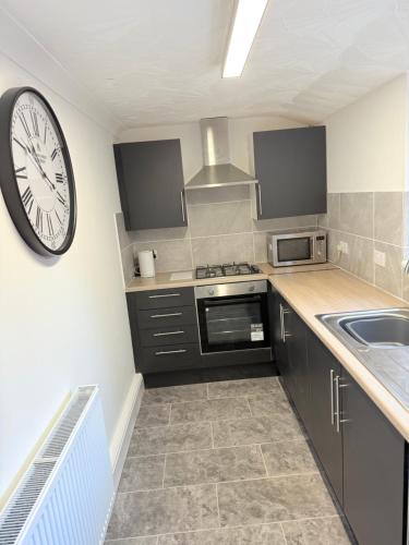 a kitchen with a large clock on the wall at 4 bedrooms 8 beds Wi-FI smart tv games room in Hull