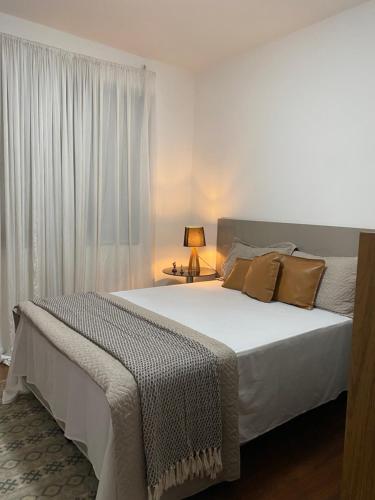 Un dormitorio con una gran cama blanca con ventana. en QUARTO ASSEMBLEIA Lourdes, en Belo Horizonte