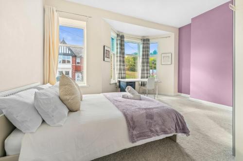 a bedroom with a large white bed with purple walls at The Royal Stay at Queens Hill Sleeps 10 in Newport