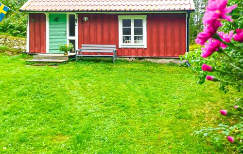 a red house with a bench in a yard at 2 Bedroom Cozy Home In Kisa in Kisa