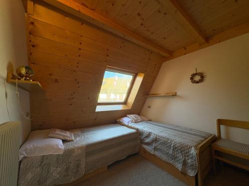 Un dormitorio con dos camas en una cabaña de madera. en Mansarda Veronza, en Castello di Fiemme