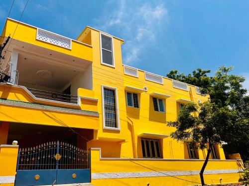a yellow building with a blue gate in front of it at Auro Breeze Villa Inn in Puducherry