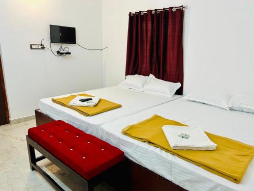 a bedroom with a large bed with a red chair at Auro Breeze Villa Inn in Puducherry