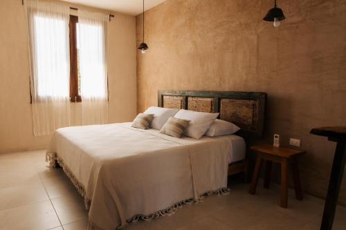 a bedroom with a bed with white sheets and a window at Izkina casa hotel centro cozumel in Cozumel