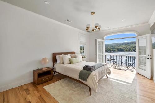 ein weißes Schlafzimmer mit Bett und Balkon in der Unterkunft Lakeview Villa with Private Hot Tub, Firepit & Breathtaking Cliff Views in Greenwood Lake