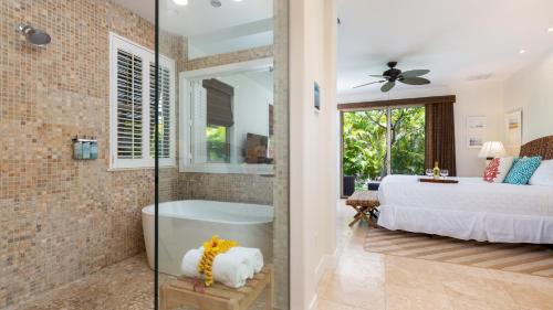 ワイコロアにあるHALE OHONU Stylish 3BR Detached Home Close to KaMilo Poolsのバスルーム(ベッド1台、バスタブ付)、ベッドルーム1室が備わります。