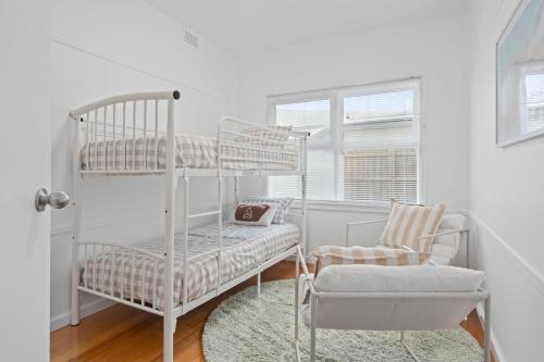 a bedroom with two bunk beds and a chair at Seascape On Cairnes in Indented Head