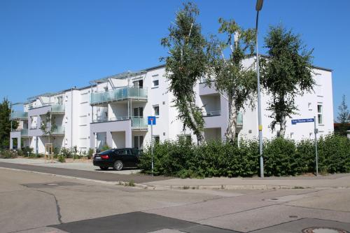 a white building with a car parked in front of it at Living Neuburg in Neuburg an der Donau