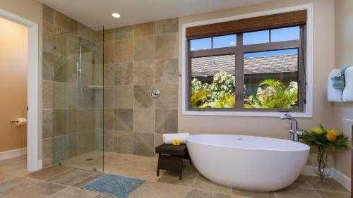 a bathroom with a tub and a glass shower at BLUE LAGOON Single Level 4BR KaMilo Home with Pool and Cottage in Waikoloa