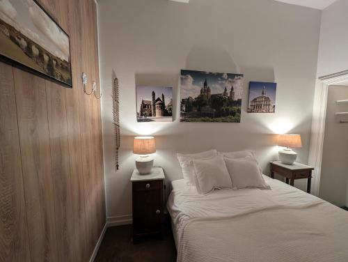 1 dormitorio con 1 cama con 2 lámparas y cuadros en la pared en Klooster Mariadal Maastricht, en Maastricht