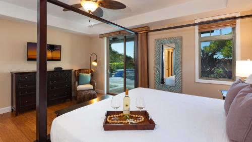 a bedroom with a white bed with a table with wine glasses at HOUSE OF JOY Light and Airy 4BR KaMilo Home with Heated Pool and Spa in Waikoloa
