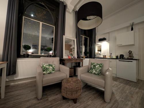 Una sala de estar con dos sillas y una cocina. en Klooster Mariadal Maastricht, en Maastricht