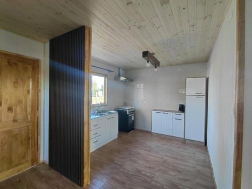 a kitchen with white cabinets and a wooden ceiling at Cabaña Aeropuerto el Tepual 3 in Puerto Montt
