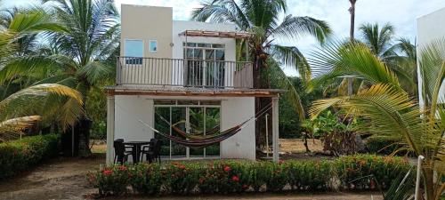 a house with a hammock in front of it at cabañas Brisas y Perla by AMAUNA in Moñitos