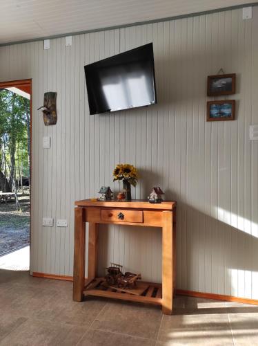 a wooden table with a television on a wall at Cabaña el Encanto in Villarrica