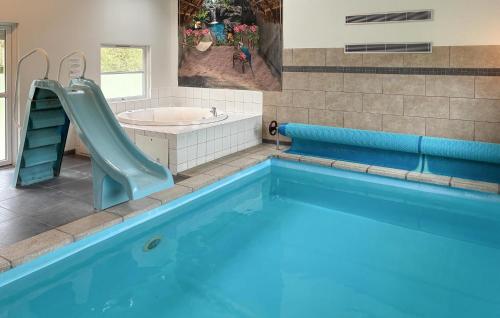 a bathroom with a swimming pool with a slide and a sink at Amazing Home In Væggerløse With Sauna in Marielyst