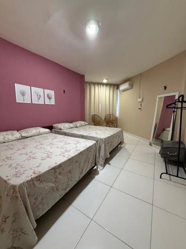 a bedroom with two beds and a purple wall at Hospedagem em frente a praia in Salinópolis