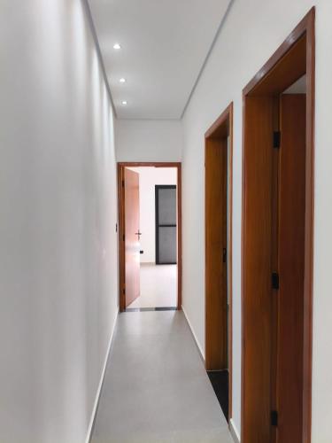 a hallway with white walls and wooden doors at Peruíbe nova in Peruíbe