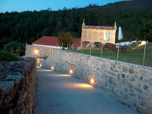 a stone wall with lights in front of a building at Casa do Fieiro in Miñortos