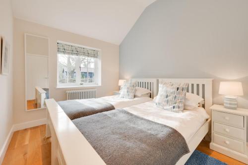 two beds in a white bedroom with a window at Sundial Lodge in Wilby