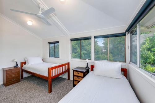 Dos camas en una habitación con ventanas. en 55 See Street Bargara, en Bargara