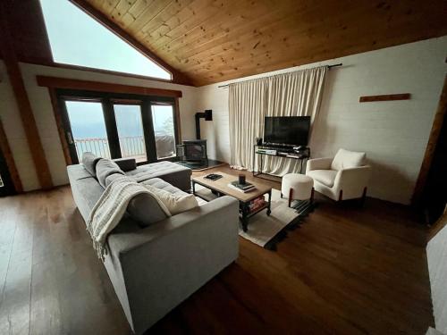 a living room with a couch and chairs and a television at Modern Mountaintop Cabin with a gorgeous view in Great Cacapon