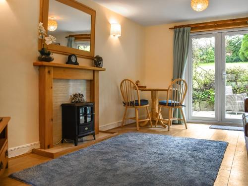 a living room with a fireplace and a table and chairs at Lower Axford Cottage in Callington