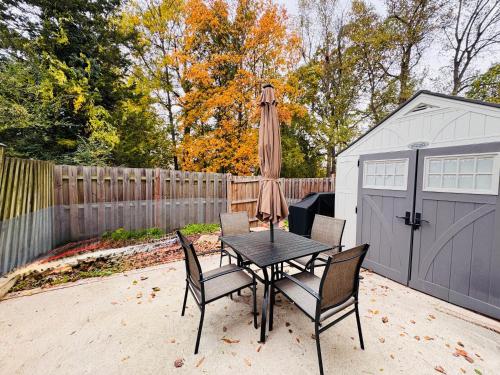 a table with chairs and an umbrella next to a garage at Charming 4BR 4BA Townhouse In Annandale, VA in Annandale