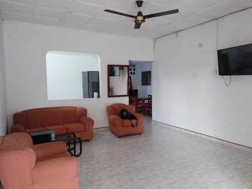 a living room with orange chairs and a flat screen tv at Casa Zona Rosa in La Dorada