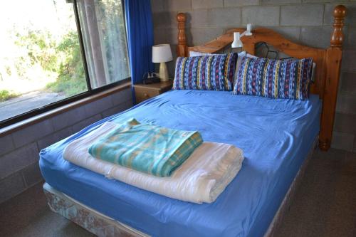 a bed with a blue sheets and pillows on it at Sound Of The Surf in Evergreen
