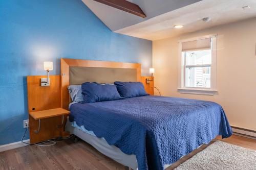 a blue bedroom with a bed and a window at Jonathan Edwards Motel in Dennis Port