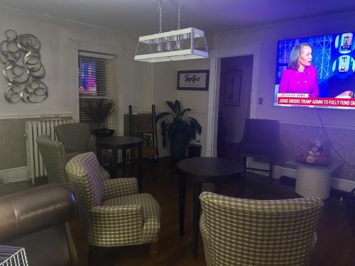 a living room with chairs and a tv with a woman on it at Sunday Morning at Savannahs in New Windsor