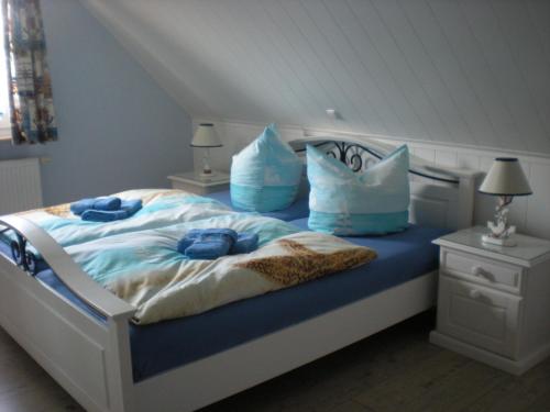 グロヴェにあるFerienhaus Arielleのベッドルーム1室(青いシーツと枕のベッド1台付)
