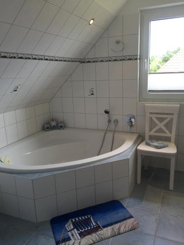 a white bathroom with a tub and a window at Ferienhaus Arielle in Glowe
