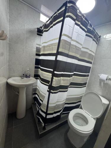 a bathroom with a shower curtain and a toilet and sink at Casa Olimpico in Cali
