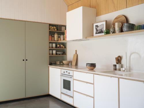 Una cocina con gabinetes blancos y una estufa. en The Hillside Project, en Frankston South