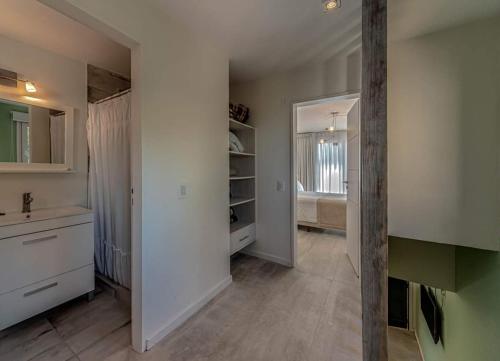 a white kitchen with a sink and a mirror at Romina Art Hotel in Villa Gesell