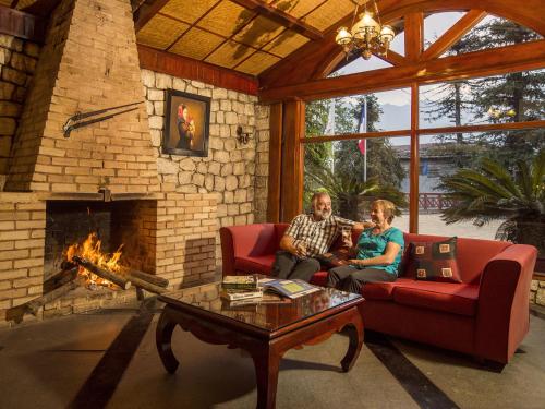 two people sitting in a living room with a fireplace at BB Sapa Resort & Spa - Formerly Victoria Sapa Resort & Spa in Sa Pa