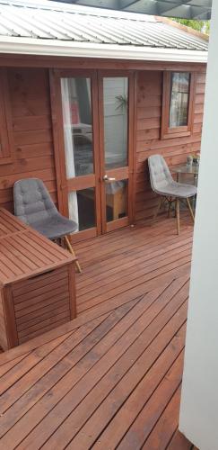 a wooden deck with two chairs and a table at Private cabin Close to airport in Auckland
