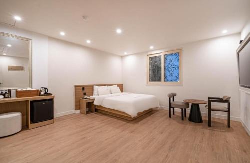 a bedroom with a bed and a desk and a table at Vov Hotel in Busan