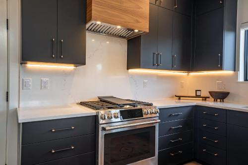 een keuken met zwarte kasten en een oven bij Lumen Haus in Maryvale