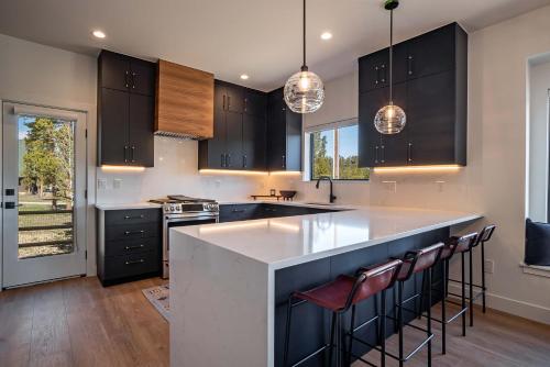 een keuken met zwarte kasten en een keukeneiland met barkrukken bij Lumen Haus in Maryvale