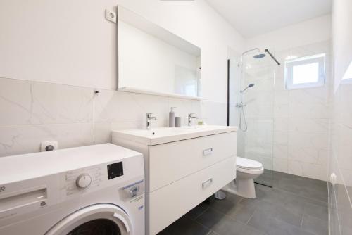 um banheiro branco com uma pia e um vaso sanitário em Family-friendly apartments with swimming pool Ljubac, Zadar - 14148 em Krneša