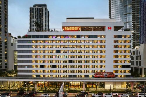 a large white building with cars parked in a parking lot at citizenM Miami Worldcenter in Miami